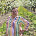 women farmworker smiling in a beautiful landscape full of crops.